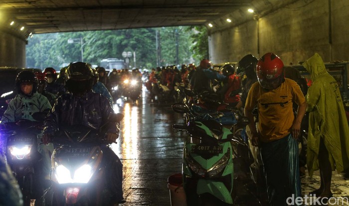 Sejumlah pemotor berteduh di kolong Tol jalan DI Panjaitan, Jakarta Timur, saat hujan turun. Akibatnya lalu lintas tersendat.