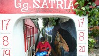 Warga melintas di gang Satria, Mampang, Jakarta, Rabu (8/11/2022). Gang yang sempit ini diramaikan dengan mural yang ciamik.