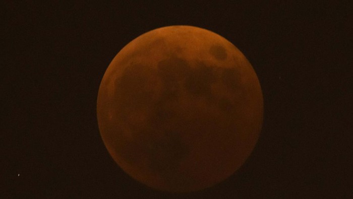 The moon rises behind a corner tower along the outer walls of the Forbidden City during a lunar eclipse in Beijing, Tuesday, Nov. 8, 2022. (AP Photo/Mark Schiefelbein)