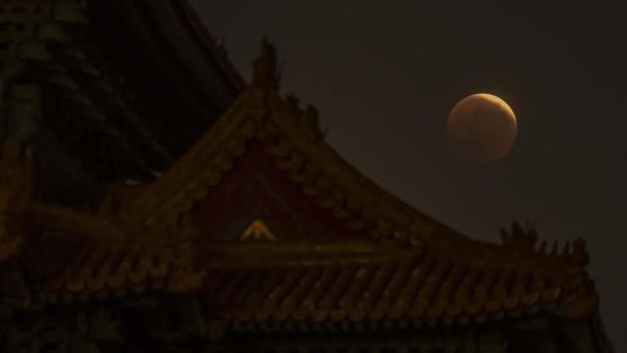 The moon rises behind a corner tower along the outer walls of the Forbidden City during a lunar eclipse in Beijing, Tuesday, Nov. 8, 2022. (AP Photo/Mark Schiefelbein)