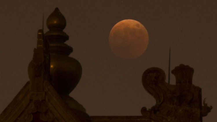 The moon rises behind a corner tower along the outer walls of the Forbidden City during a lunar eclipse in Beijing, Tuesday, Nov. 8, 2022. (AP Photo/Mark Schiefelbein)