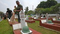 Anggota TNI menyapu dan rumput-rumput kering yang ada di area makam.