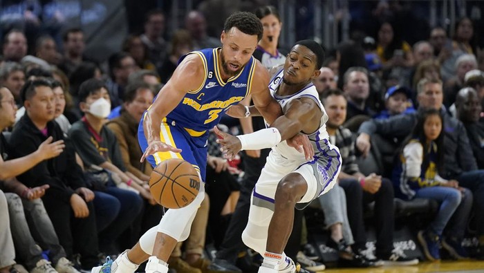 Golden State Warriors guard Stephen Curry, left, reaches for the ball while defended by Sacramento Kings guard DeAaron Fox during the first half of an NBA basketball game in San Francisco, Monday, Nov. 7, 2022. (AP Photo/Jeff Chiu)