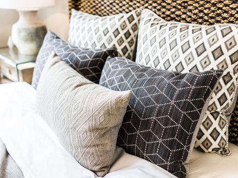 Closeup of new bed comforter with decorative pillows, headboard in bedroom in staging model home, house or apartment