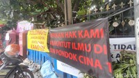 Spanduk protes juga terpasang di depan SDN Pocin 1. Orang tua siswa belum sepakat dengan relokasi (Dwi Rahmawati/detikcom)