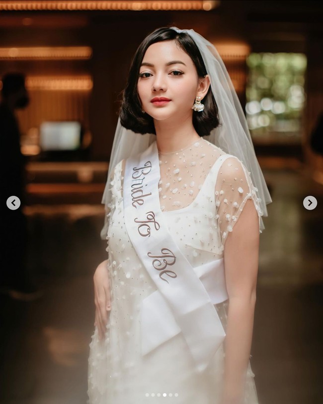Glenca tampil cantik mengenakan dress berwarna putih. Seperti dalam acara bridal shower pada umumnya, Glenca yang merupakan calon pengantin juga mengenakan veil di rambut dan selempang yang bertuliskan Bride To Be. Foto: Instagram/@glencachysara