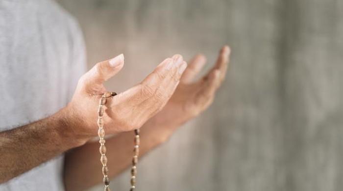 Muslim man praying with prayer beads beads in hand for copy space