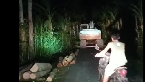 Eskavator untuk mengeruk bukit di wilayah Desa Adat Pangi, Klungkung, terekam warga sedang melintas di jalan desa malam hari.
