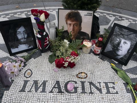 Photos, flowers and candles are left at Strawberry Fields in New York's Central Park to remember John Lennon, Tuesday, Dec. 8, 2020, in New York. The rock star and former Beatle was shot to death outside his New York City apartment building by a fan on Dec. 8, 1980. (AP Photo/Mark Lennihan)