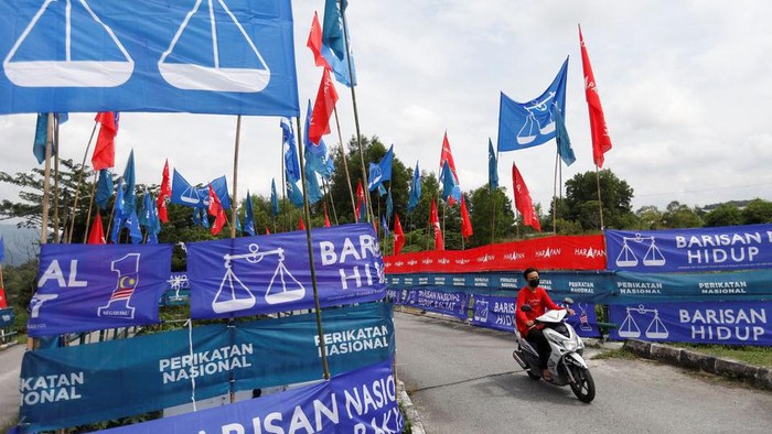 A motorcyclist rides past the party flags and banners during the campaign period of Malaysias general election in Ipoh, Perak, Malaysia November 6, 2022. REUTERS/Hasnoor Hussain