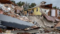 Pemilik rumah berdiri di atas rumahnya yang rusak akibat hantaman badai Nicole. (Joe Raedle/Getty Images)