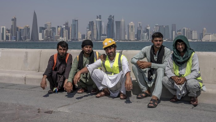 FILE - Pakistani migrant laborers pose for a photograph, as they take a break, on the corniche, overlooking the skyline of Doha, Qatar, Wednesday, Oct. 19, 2022. Migrant laborers who built Qatars World Cup stadiums often worked long hours under harsh conditions and were subjected to discrimination, wage theft and other abuses as their employers evaded accountability, a rights group said in a report released Thursday. (AP Photo/Nariman El-Mofty, File)