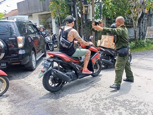 Petugas Linmas Desa Tibuneneng, Kecamatan Kuta Utara, Badung, mengarahkan kendaraan di simpang Pura Puseh, Jumat (11/11/2022). Foto: Agus Eka