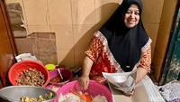 Ini dia sosok utama di balik Sego Banting Cak San. Namanya Ibu Sunarsih yang terbiasa duduk saat meracik nasi bungkus.