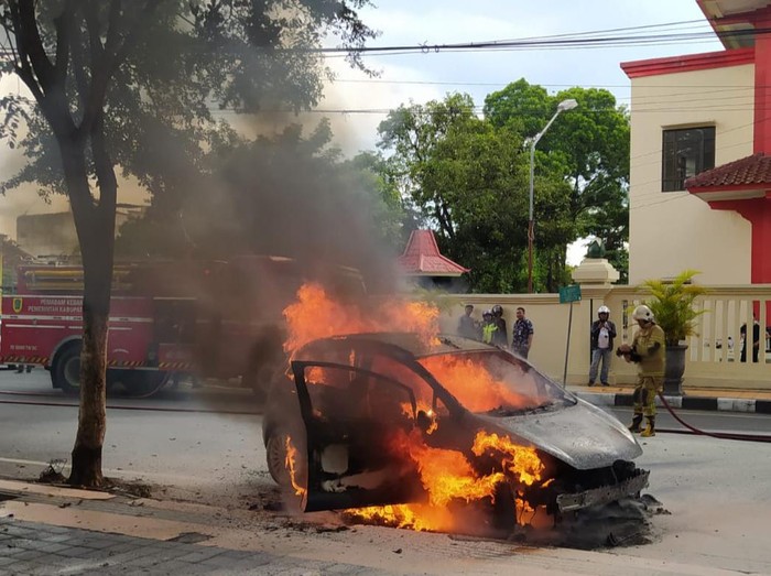 Regu pemadam Pemkab Klaten berupaya memadamkan mobil yang terbakar di Jalan Merapi, Klaten Tengah, Sabtu (12/11/2022) siang.