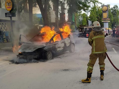 Regu pemadam Pemkab Klaten berupaya memadamkan mobil yang terbakar di Jalan Merapi, Klaten Tengah, Sabtu (12/11/2022) siang.
