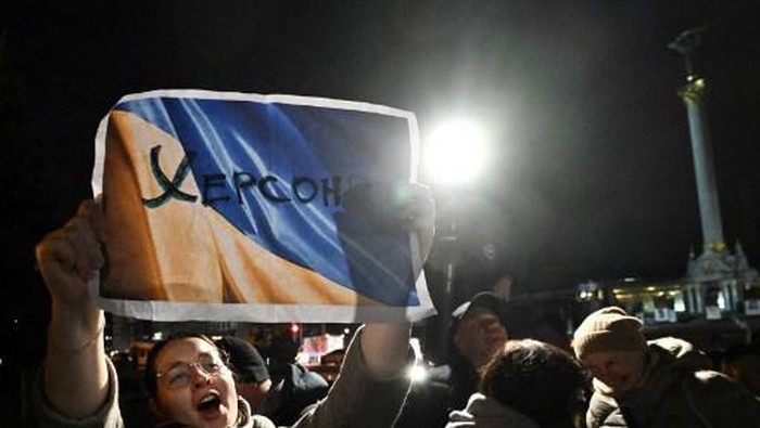 People hold a Ukranian flag as they gather in Maidan square to celebrate the liberation of Kherson, in Kyiv on November 11, 2022, amid the Russian invasion of Ukraine. - Ukraines President Volodymyr Zelensky said on November 11 that Kherson was 
