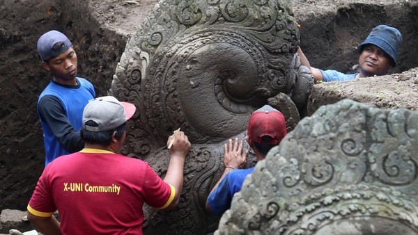 Arkeolog dari Badan Riset dan Inovasi Nasional (BRIN) dibantu pekerja membersihkan arca saat ekskavasi di Situs Adan-adan, Desa Adan-adan, Kediri, Jawa Timur, Sabtu (12/11/2022).