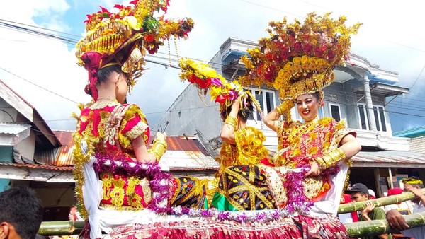 Dalam Parade Karia, anak-anak mengenakan pakaian tradisional berwarna-warni, memakai hiasan kepala berbentuk bunga dan aksesoris emas.