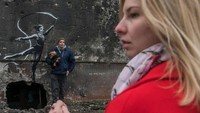 Warga di dekat Kyiv, Ukraina, terlihat hendak mengabadikan momen swafoto bersama karya mural dari Banksy, Sabtu (12/11/2022).