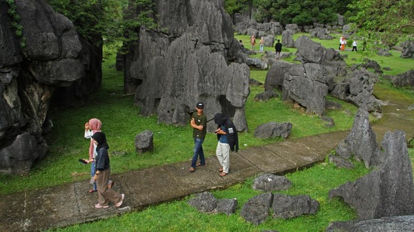Sejumlah pengunjung melintas di area Taman Prasejarah Leang-Leang di Kabupaten Maros, Sulawesi Selatan, Minggu (13/11/2022). Jumlah kunjungan rata-rata wisatawan mencapai 800 orang lho per pekan.