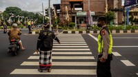 Para pecalang dan petugas polisi bersinergi mengatur lalu lintas.