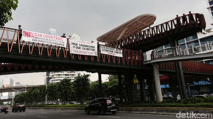 Sejumlah aktivis membentangkan spanduk sebagai bentuk protes terhadap komitmen anggota G20 dalam melawan perubahan iklim di JPO Pinisi, Jalan Sudirman, Jakarta, Senin (14/11/2022). Bali kembali akan menjadi saksi komitmen-komitmen kepala negara. Kali ini pertemuan negara G20 yang merupakan penyumbang 80% emisi dunia dan merupakan penghuni 60% populasi bumi.