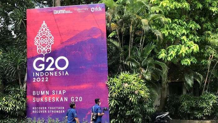 Orang-orang berjalan melewati spanduk berlogo G20 di Bali