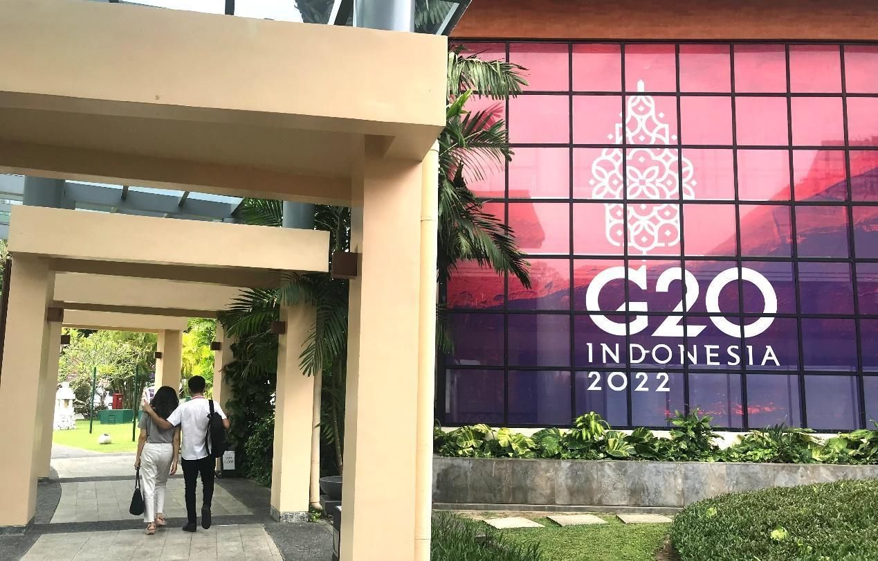 Orang-orang berjalan melewati spanduk berlogo G20 di Bali