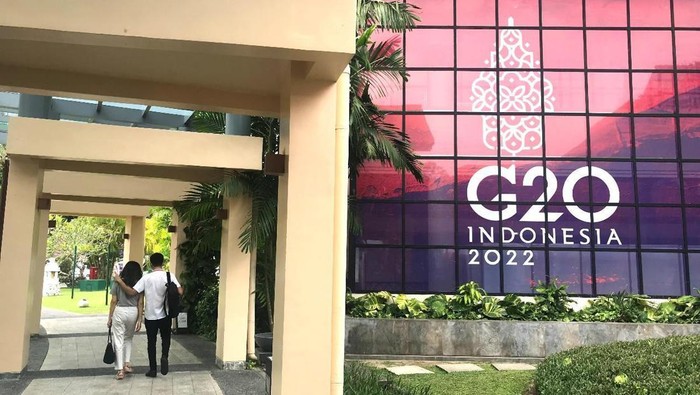 Orang-orang berjalan melewati spanduk berlogo G20 di Bali