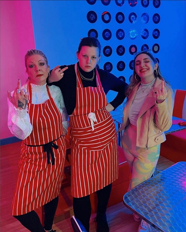 Bertolak belakang dengan sikap staf yang selalu marah-marah, seragam mereka justru kental nuansa ceria. Para pelayan Karen’s Diner biasanya memakai kemeja putih yang dilengkapi apron berwarna cerah dan motif atraktif. Foto: Instagram/@karensdinerofficial