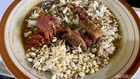 Rawon disajikan bersama topping tauge pendek di sisian dan kumpulan potongan daging di tengah piring. Ada juga sambal merahnya yang menggugah selera. 