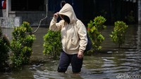 Akses jalan terputus, warga pun berjalan kaki melintasi banjir. 