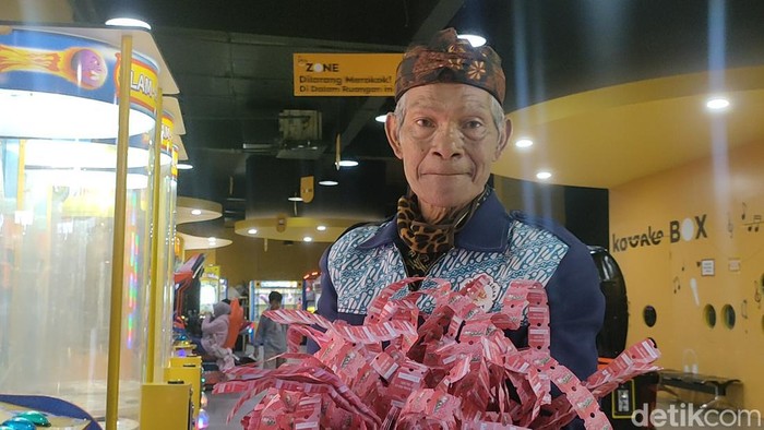 Abah Empit menunjukkan hadiah yang ia terima saat bermain mesin permainan di Garut