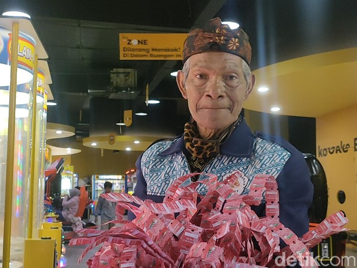 Abah Empit menunjukkan hadiah yang ia terima saat bermain mesin permainan di Garut