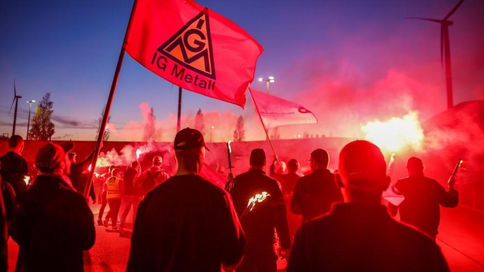 14 November 2022, Saxony, Leipzig: BMW employees leave the Leipzig plant with flags and banners for a warning strike. IG-Metall had called for the warning strike during the ongoing third round of collective bargaining in the metal and electrical industry. The union is demanding eight percent higher wages and salaries in response to price increases. Photo: Jan Woitas/dpa (Photo by Jan Woitas/picture alliance via Getty Images)