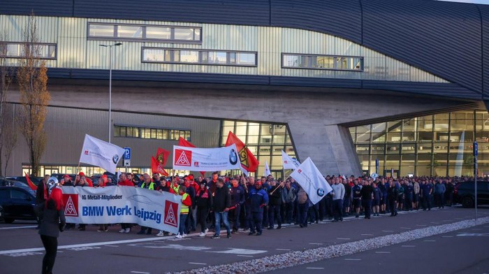 14 November 2022, Saxony, Leipzig: BMW employees leave the Leipzig plant with flags and banners for a warning strike. IG-Metall had called for the warning strike during the ongoing third round of collective bargaining in the metal and electrical industry. The union is demanding eight percent higher wages and salaries in response to price increases. Photo: Jan Woitas/dpa (Photo by Jan Woitas/picture alliance via Getty Images)
