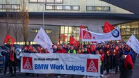 Karyawan BMW meninggalkan pabrik Leipzig dengan membawa bendera dan spanduk untuk mogok kerja, Senin, (14/11/2022).