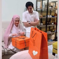 Dalam unggahan di Instagram Story terlihat Rey Mbayang memberikan kado yang tak kaleng-kaleng untuk sang istri. Pria 24 tahun itu tampak memberikan kado spesial berupa barang mewah dari Hermes untuk Dinda. Dinda pun mengungkapkan kebahagiaan dan rasa terima kasihnya untuk sang suami di dalam keterangan pada foto tersebut. Foto: Instagram/@rey_mbayang