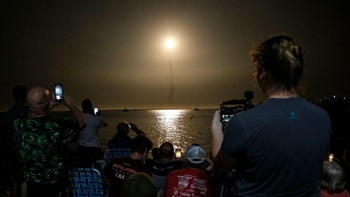 Warga sekitar menyaksikan dan mengabadikan momen bersejarah ini dari kejauhan. Misi Artemis 1 akan diikuti oleh beberapa misi lagi menuju Bulan, termasuk misi Artemis 3 yang akan mendaratkan astronaut ke permukaan Bulan. Foto: MARCO BELLO/AFP via Getty Images