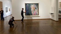 Tampak seorang pria mendekati lukisan Gustav Klimt Tod und Leben dengan membawa wadah berisi cairan hitam berminyak.