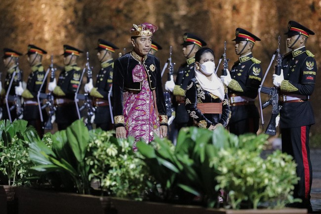 Iriana Jokowi mengenakan kebaya hitam berhias bordiran bunga warna emas dengan aksen kain yang diikat pada pinggang. Kebaya dipadankan dengan songket Bali warna fuchsia. Ia juga memakai kerudung warna pastel. Foto: Dok. AP