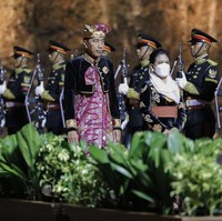 Iriana Jokowi mengenakan kebaya hitam berhias bordiran bunga warna emas dengan aksen kain yang diikat pada pinggang. Kebaya dipadankan dengan songket Bali warna fuchsia. Ia juga memakai kerudung warna pastel. Foto: Dok. AP