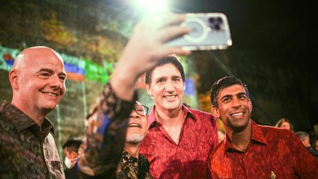 15 November 2022, Indonesia, Nusa Dua: Wearing traditional shirts, Giovanni Infantino (l-r), Fifa president, Justin Trudeau, prime minister of Canada, and Rishi Sunak, prime minister of Great Britain, attend dinner on the sidelines of the G20 summit. In the process, another participant takes a selfie. The group of the G20, the strongest industrialized nations and emerging economies, is meeting for two days on the Indonesian island of Bali. Photo: Kay Nietfeld/dpa (Photo by Kay Nietfeld/picture alliance via Getty Images)