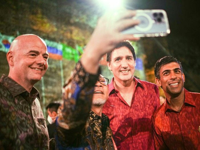 15 November 2022, Indonesia, Nusa Dua: Wearing traditional shirts, Giovanni Infantino (l-r), Fifa president, Justin Trudeau, prime minister of Canada, and Rishi Sunak, prime minister of Great Britain, attend dinner on the sidelines of the G20 summit. In the process, another participant takes a selfie. The group of the G20, the strongest industrialized nations and emerging economies, is meeting for two days on the Indonesian island of Bali. Photo: Kay Nietfeld/dpa (Photo by Kay Nietfeld/picture alliance via Getty Images)