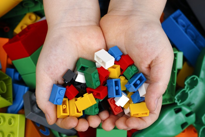 Tambov, Russian Federation - February 20, 2015 Lego Bricks in childs hands with Lego Duplo blocks and toys background. Studio shot.