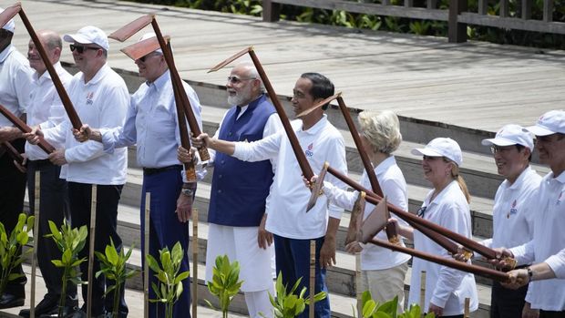 From left, German Chancellor Olaf Scholz, Australian Prime Minister Anthony Albanese, US President Joe Biden, Indian Prime Minister Narendra Modi, Indonesian President Joko Widodo, European Commission President Ursula von der Leyen, the Italian Prime Minister Giorgia Meloni, Japanese Prime Minister Fumio Kishida, and Spanish Prime Minister Pedro Sanchez raise shovels as they visit a mangrove planting area as part of the G20 summit in Denpasar, Bali, Indonesia on Wednesday, November 16, 2022 (AP Photo/Dita Alangkara, Pool)