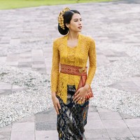 Maudy Ayunda kembali mempercayakan Didiet Maulana untuk merancang busananya. Kebaya warna mustard ini terlihat unik dengan model kerah asimetris. Obi merah dari tenun berbordir emas mengaksentuasi pinggang. Foto: Instagram @maudyayunda
