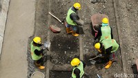 Petugas tampak mengangkat bebatuan yang menimbun rel trem.