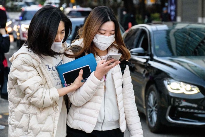 A student (R) arrives to sit for the annual college entrance exam, known locally as 'Suneung', outside the Ehwa Girls Foreign Language High School in Seoul on November 17, 2022. (Photo by Anthony WALLACE / AFP) (Photo by ANTHONY WALLACE/AFP via Getty Images)
